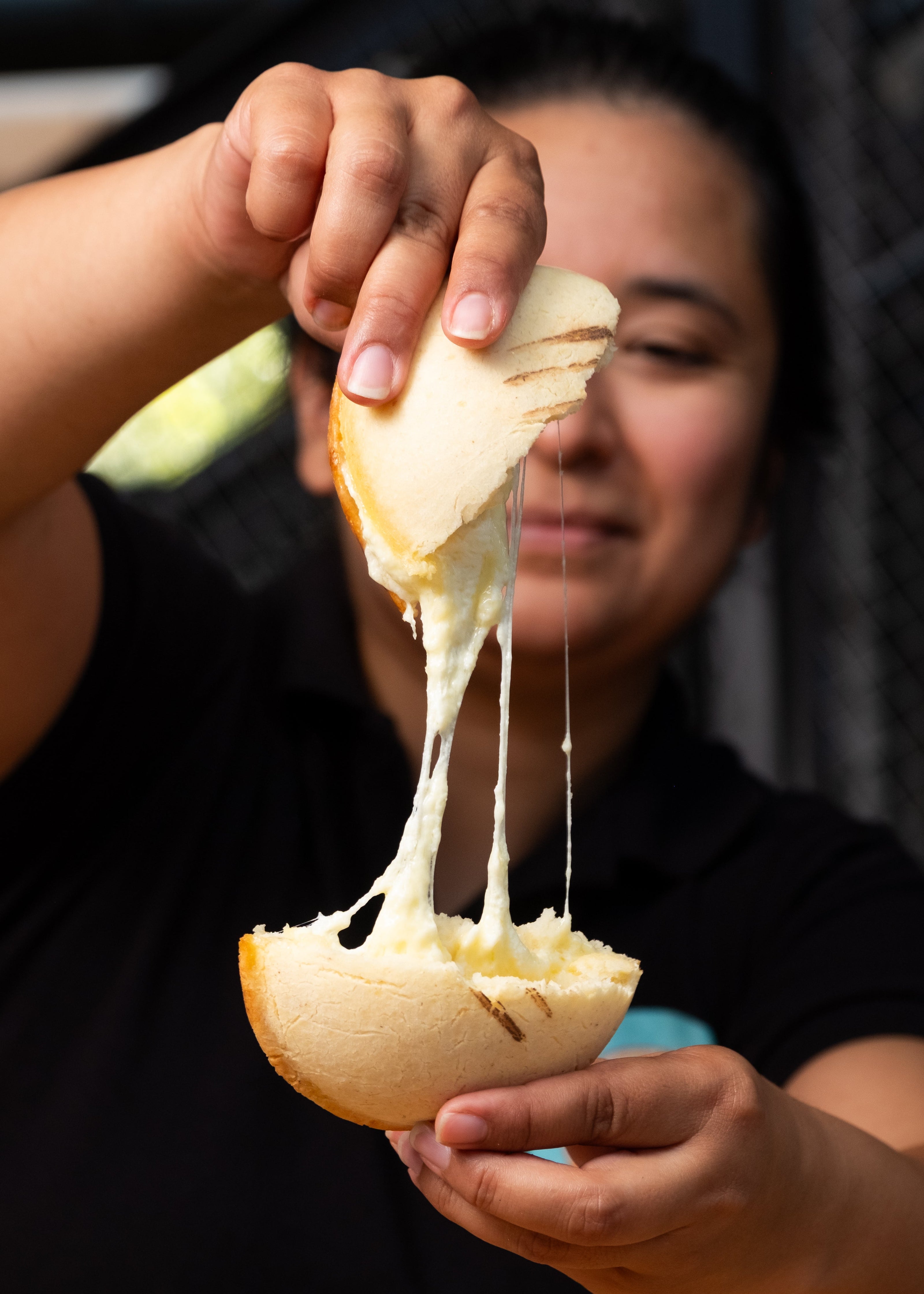 Person holding a sliced bread with cheese stretching from it - Poderosa